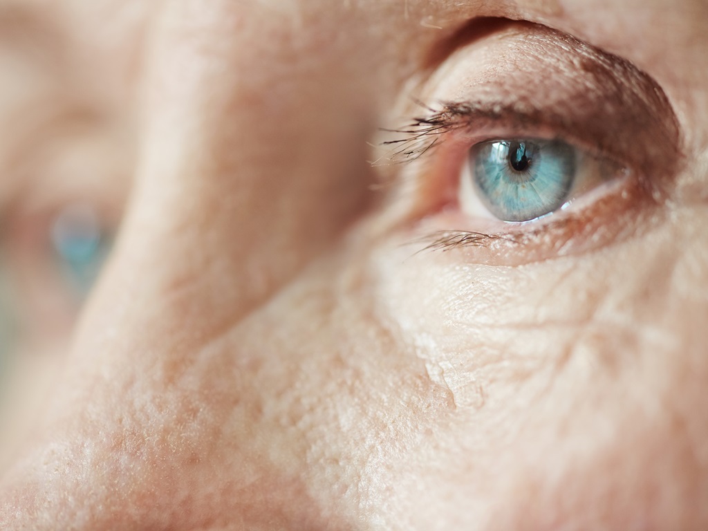 Extreme Nahaufnahme von traurigen blauen Augen auf faltigem Frauengesicht, das in die Ferne schaut
